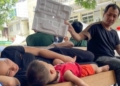 Ông bố ngồi dưới gốc cây ở bệnh viện, chăm con trai ngủ giữa ngày nắng đỉnh điểm