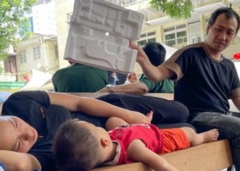 Ông bố ngồi dưới gốc cây ở bệnh viện, chăm con trai ngủ giữa ngày nắng đỉnh điểm
